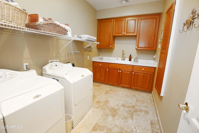 clothes washing area featuring cabinets, washing machine and clothes dryer, and sink