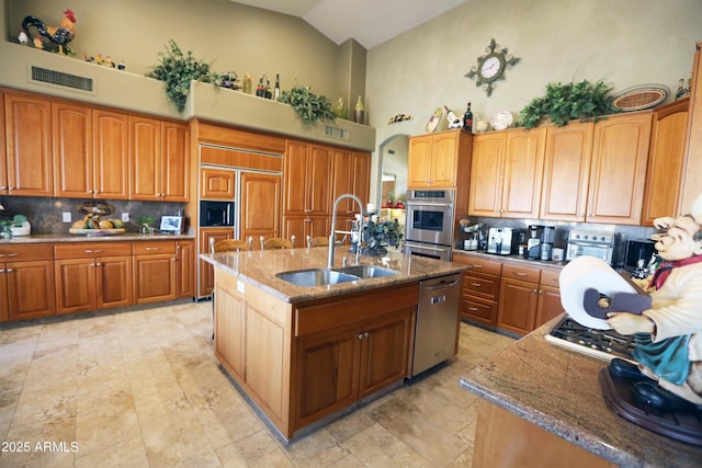 kitchen with stone countertops, sink, an island with sink, and appliances with stainless steel finishes