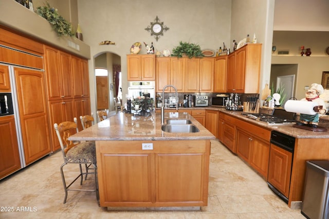 kitchen featuring sink, a breakfast bar area, a center island with sink, stainless steel gas stovetop, and white oven