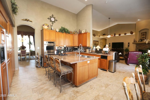 kitchen featuring high vaulted ceiling, sink, a kitchen bar, a kitchen island with sink, and kitchen peninsula