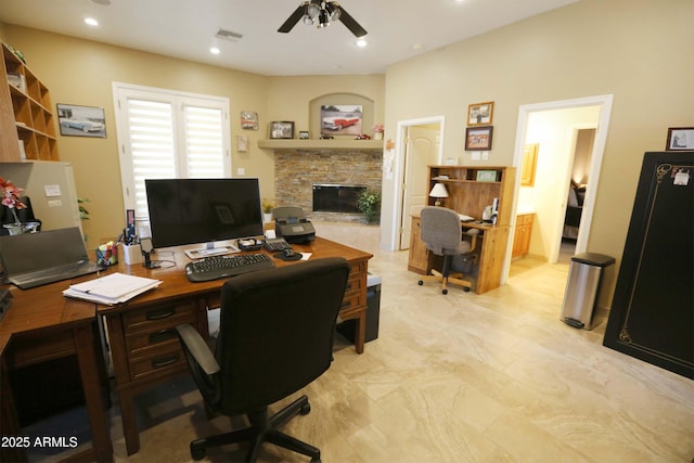 office space with a stone fireplace and ceiling fan