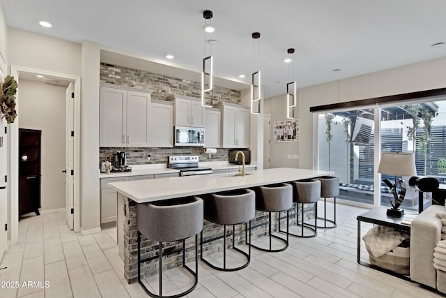 226 E Markwood Dr, Chandler, AZ 85286 - kitchen featuring stainless steel appliances, light countertops, a breakfast bar area, tasteful backsplash, and a center island with sink