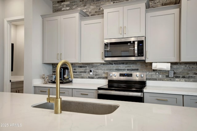 226 E Markwood Dr, Chandler, AZ 85286 - kitchen featuring stainless steel appliances, a sink, backsplash, light stone counters, and gray cabinetry