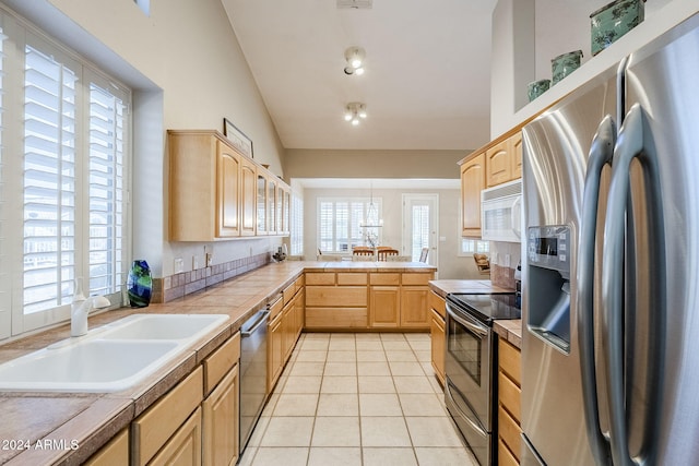 kitchen featuring appliances with stainless steel finishes, light brown cabinetry, sink, tile counters, and light tile patterned flooring