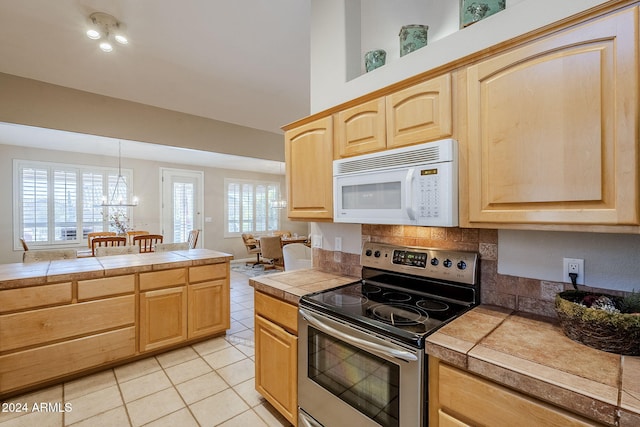 kitchen featuring tile counters, light brown cabinets, and stainless steel range with electric cooktop