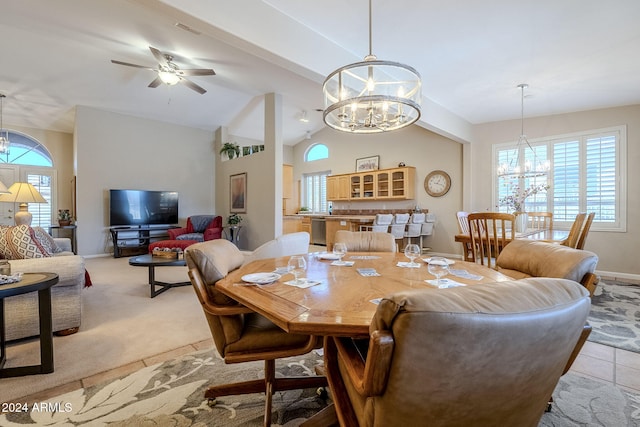 dining space featuring ceiling fan with notable chandelier, light tile patterned floors, and lofted ceiling