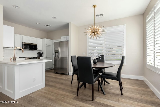 dining space with sink, a chandelier, and light hardwood / wood-style floors