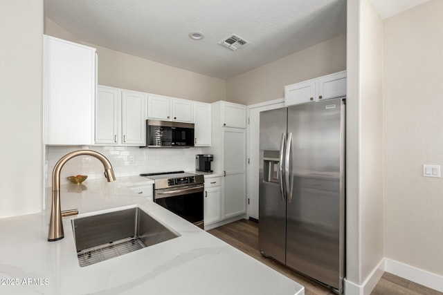 kitchen featuring appliances with stainless steel finishes, tasteful backsplash, sink, white cabinets, and dark wood-type flooring