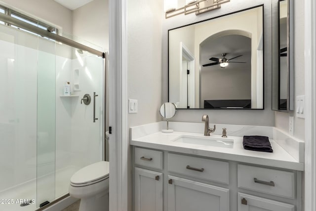 bathroom with vanity, toilet, ceiling fan, and a shower with shower door