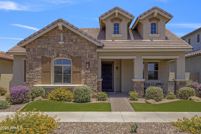 4302 E Cynthia St, Gilbert, AZ 85295 - view of front of house featuring a porch, a tile roof, stone siding, and stucco siding