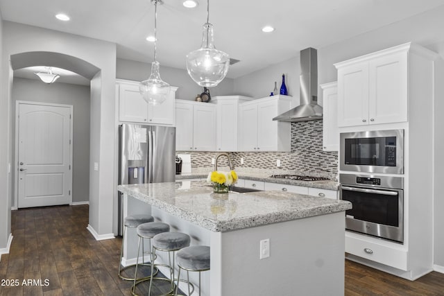 4302 E Cynthia St, Gilbert, AZ 85295 - kitchen with stainless steel appliances, wall chimney exhaust hood, arched walkways, tasteful backsplash, and white cabinetry