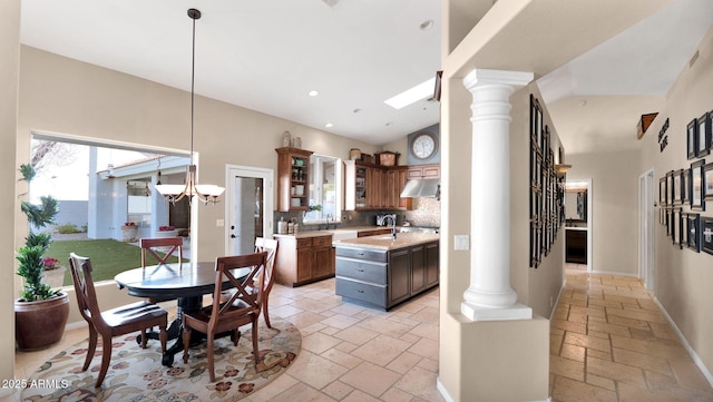 kitchen featuring hanging light fixtures, decorative columns, light stone counters, tasteful backsplash, and a kitchen island