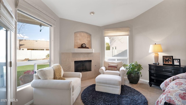 carpeted living room featuring lofted ceiling and a tile fireplace