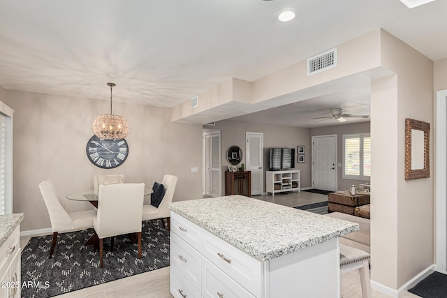 kitchen with pendant lighting, a center island, light hardwood / wood-style floors, white cabinets, and a kitchen bar