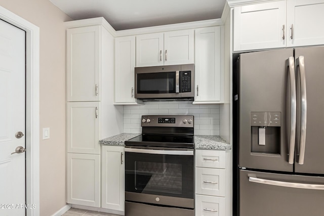 kitchen featuring tasteful backsplash, light stone countertops, white cabinets, and appliances with stainless steel finishes