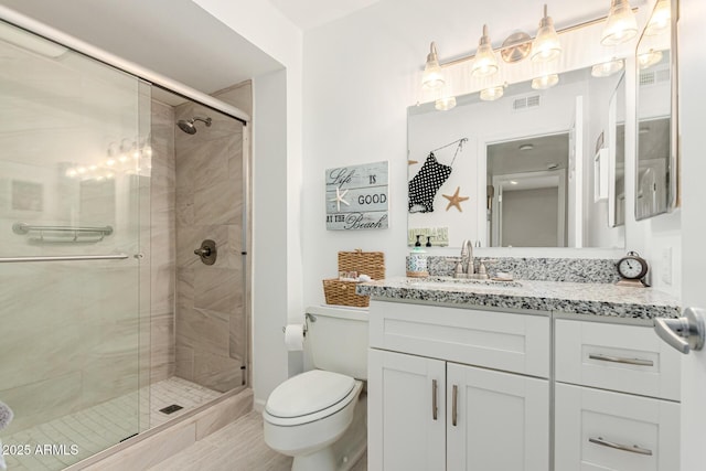 bathroom with vanity, a shower with door, and toilet