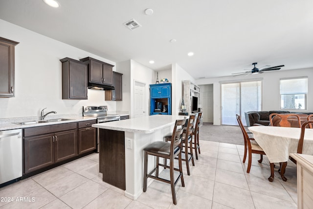 kitchen featuring a center island, stainless steel appliances, sink, a kitchen breakfast bar, and ceiling fan