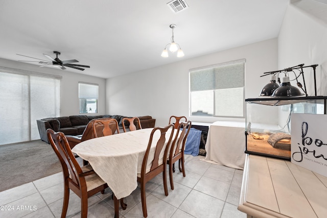 dining area with ceiling fan with notable chandelier and light tile patterned floors