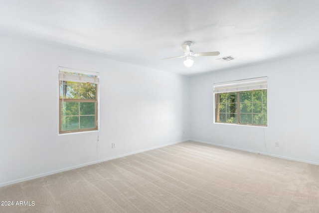 spare room with a wealth of natural light, ceiling fan, and light carpet