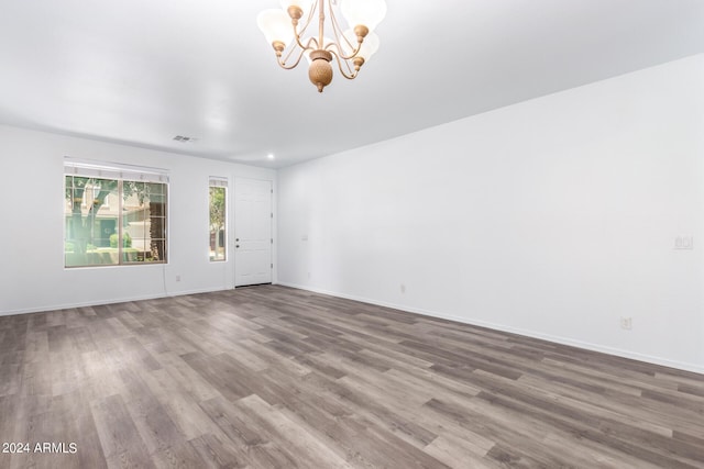 spare room featuring a chandelier and wood-type flooring