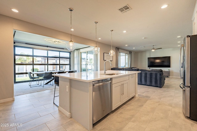 kitchen featuring white cabinetry, visible vents, a sink, stainless steel appliances, and open floor plan