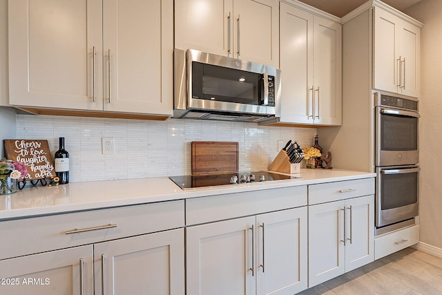 kitchen featuring backsplash, light countertops, appliances with stainless steel finishes, and light wood-type flooring