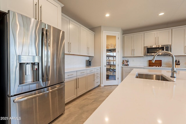 kitchen featuring light countertops, tasteful backsplash, a sink, and stainless steel appliances