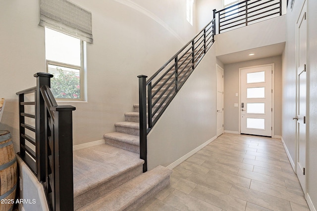 foyer entrance featuring a high ceiling, baseboards, and stairs