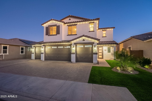 mediterranean / spanish home with a tile roof, decorative driveway, a garage, and stucco siding