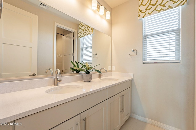 bathroom featuring double vanity, visible vents, baseboards, and a sink