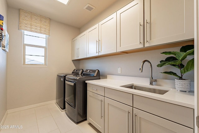 washroom featuring independent washer and dryer, visible vents, a sink, baseboards, and cabinet space