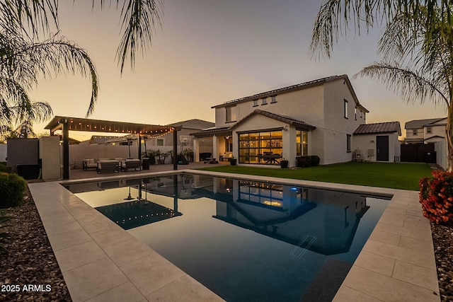 pool at dusk with an outdoor hangout area, a pergola, a yard, a fenced backyard, and a patio area