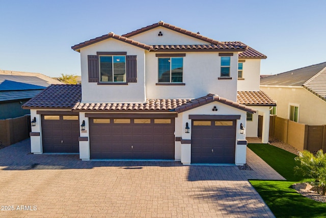 mediterranean / spanish-style house with an attached garage, stucco siding, fence, and a tile roof