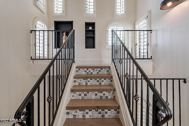 staircase with hardwood / wood-style floors and a high ceiling