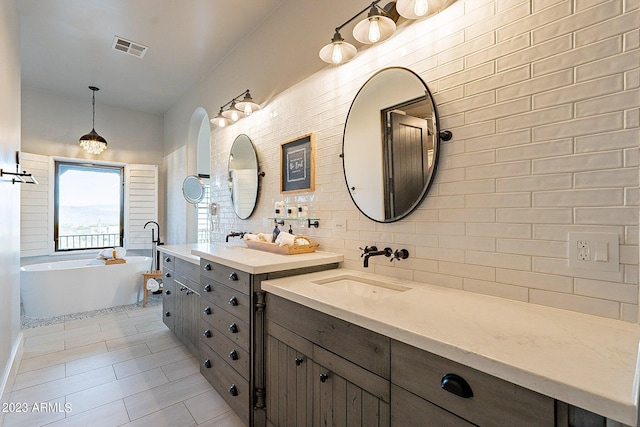 bathroom featuring tile patterned floors, vanity, backsplash, and a bath