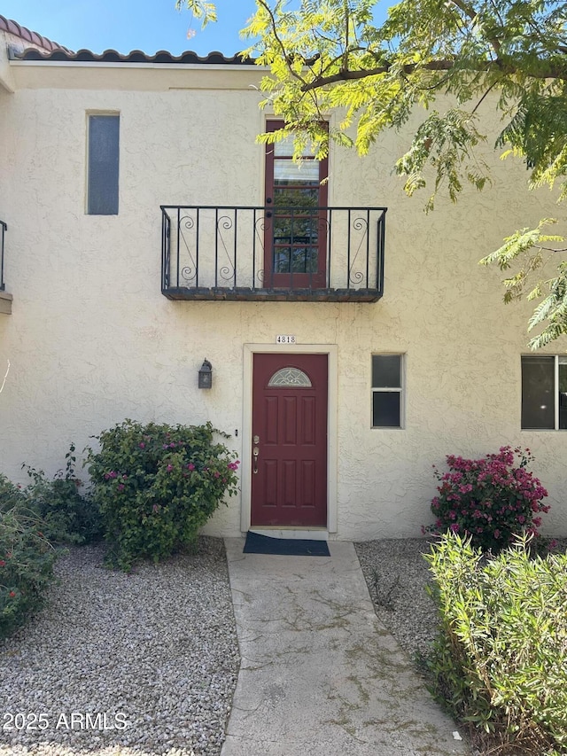 entrance to property with stucco siding and a balcony