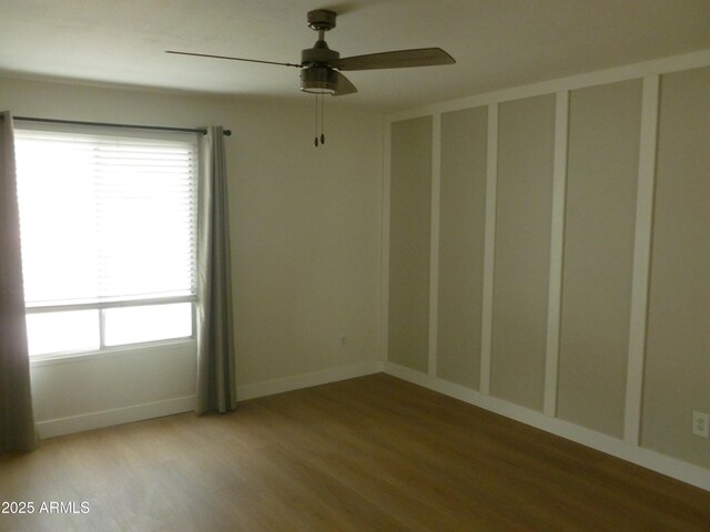 empty room featuring baseboards, wood finished floors, and a ceiling fan