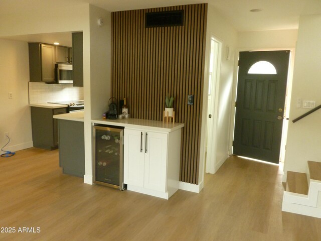 entryway with beverage cooler, a dry bar, light wood-type flooring, and baseboards