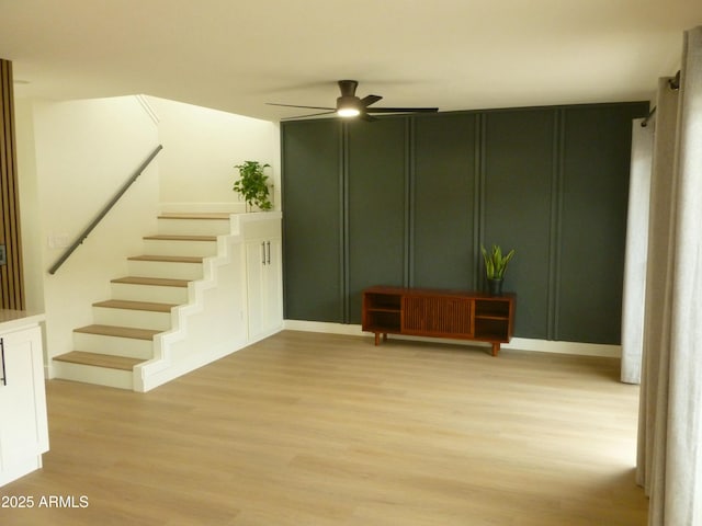 interior space featuring a decorative wall, a ceiling fan, and wood finished floors