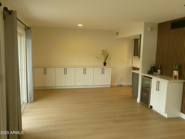 kitchen featuring baseboards, wine cooler, light countertops, light wood-type flooring, and recessed lighting