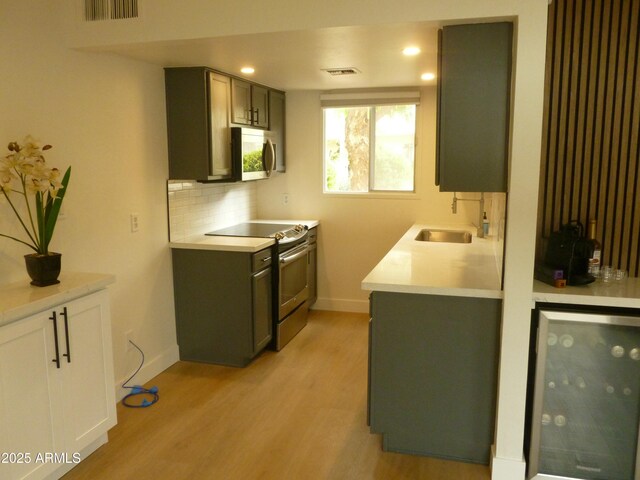 kitchen featuring a sink, stainless steel appliances, wine cooler, and visible vents