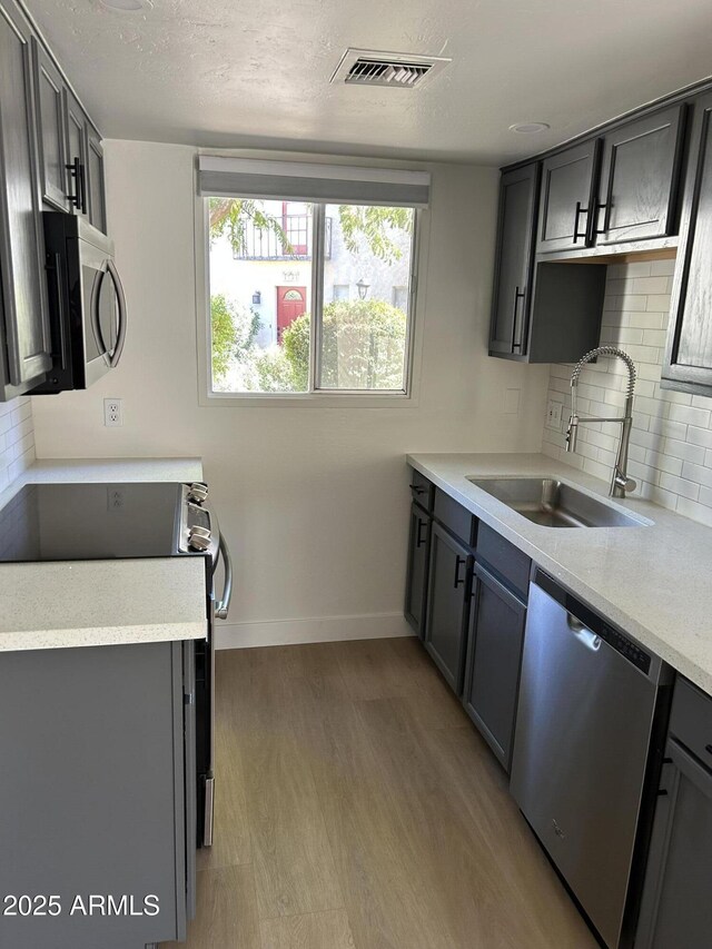 kitchen featuring visible vents, light wood finished floors, a sink, light countertops, and appliances with stainless steel finishes