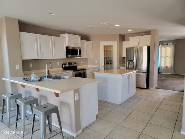 kitchen featuring a kitchen island, appliances with stainless steel finishes, sink, and white cabinets