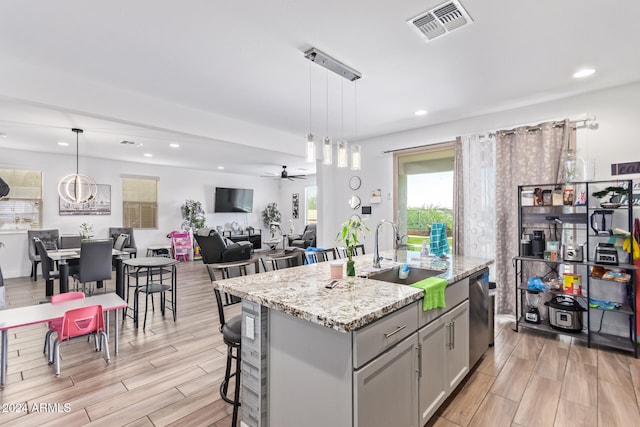 kitchen featuring sink, gray cabinetry, hanging light fixtures, a center island with sink, and dishwasher