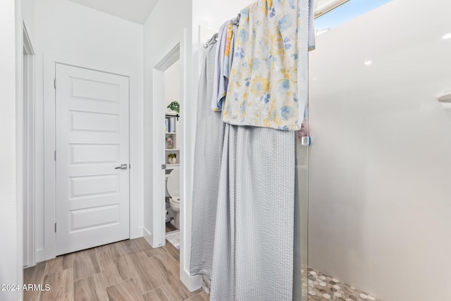 bathroom with walk in shower, toilet, and hardwood / wood-style floors