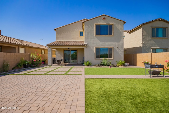 back of house with ceiling fan, a patio, and a lawn