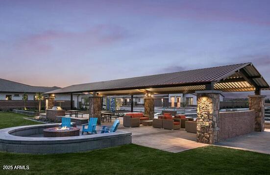 patio terrace at dusk featuring a gazebo, a yard, and a fire pit