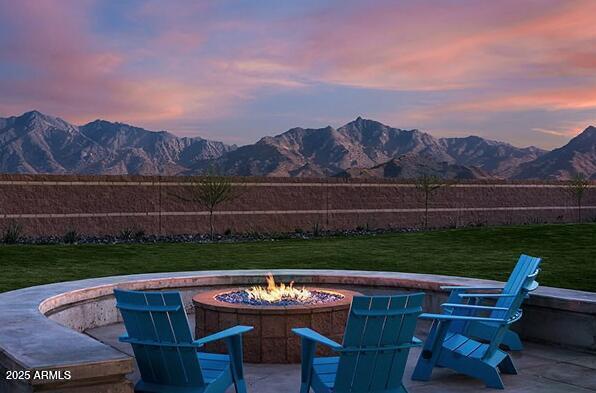 patio terrace at dusk featuring a mountain view, a yard, and an outdoor fire pit