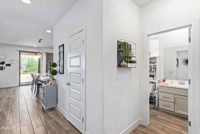 corridor with sink and light hardwood / wood-style flooring