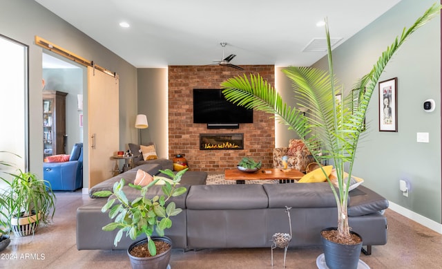 carpeted living room with a barn door, a fireplace, and ceiling fan